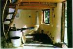 Interior: Barrel stove, heated cob bench, and stabilized earth floor.